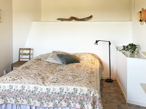 A bedroom with a bed, a chair, a desk, a lamp, and a plant. - Holiday Home in Åskloster (Åskloster)