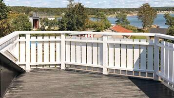 A wooden deck with a white railing overlooking a body of water and a forested area.