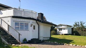 A white two-story house with a balcony, a small attached garage, and a gravel driveway.