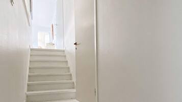 A white interior hallway with a staircase leading to a door.
