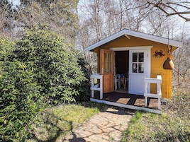 A small wooden cabin with a white porch, a door, and a window.