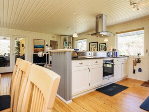 Una cocina moderna con pisos de madera, armarios blancos y una isla central.
