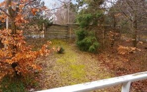 A fenced yard with a wooden fence, a small tree, and a grassy area.