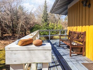 A wooden deck with a bench and a table holding two bread loaves. - Cozy Holiday Home in Graested near Sea (Graested)