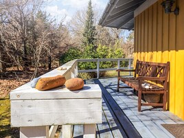 A wooden deck with a bench and a table holding two bread loaves.