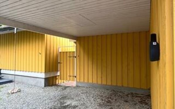 A building with a yellow exterior, a concrete base, and a gravel ground.