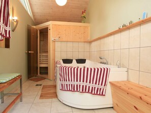 A room with a wooden bench, a white bathtub, and a wooden door leading to a sauna. - Cozy Holiday Home in Graested near Sea (Graested)
