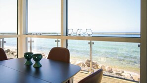 Zona de dinar amb vista al mar, una taula amb caires i una barana amb gots.