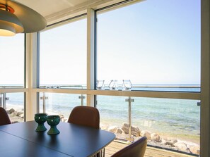 A dining area with a view of the sea, a table with chairs, and a railing with glasses. - Sunlit Holiday Home in Bornholm near Sea (Ronne)