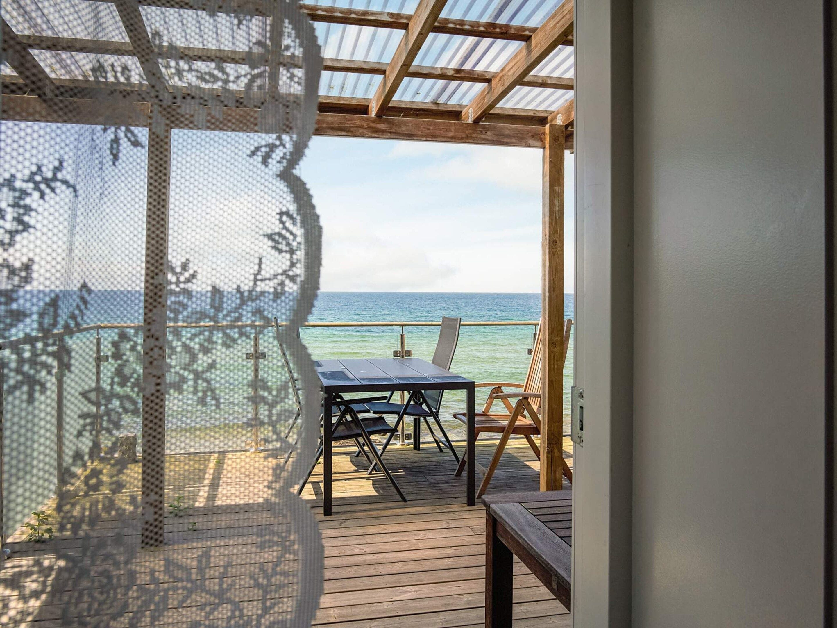 Une terrasse en bois avec une table et des chaises, donnant sur la mer.