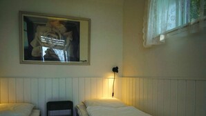 Una habitació amb dos llits individuals, una tauleta de nit, una làmpada i un quadre al mur.