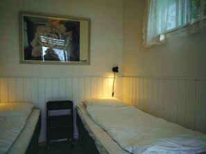 A room with two single beds, a nightstand, a lamp, and a framed picture on the wall. - Sunlit Holiday Home in Bornholm near Sea (Ronne)