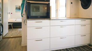 Cuina amb armaris blancs, un forn Siemens i un llum penjant.