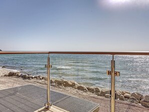 Une vue sur la plage, avec une rambarde en métal et une zone sablonneuse.