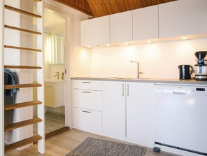 A modern kitchen with white cabinets, a built-in dishwasher, and a coffee maker. - Sunlit Holiday Home in Bornholm near Sea (Ronne)