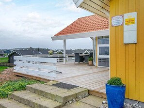 A covered outdoor area with a wooden deck, a white fence, and a blue planter. - 8 Person Holiday Home in Nordborg-by Traum (Nordborg)