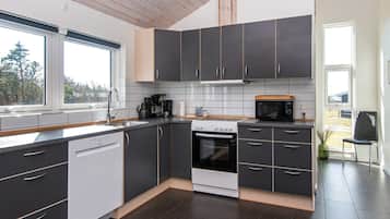 Cozinha moderna com armários escuros, forno embutido, micro-ondas e máquina de café.