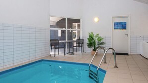 An indoor swimming pool with a metal ladder, a door with a sign, and a potted plant. - 5 Star Holiday Home in Logstor (Logstor)