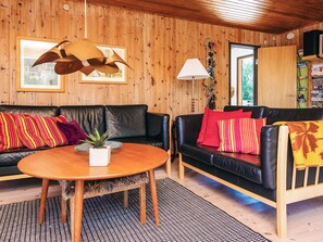Ein gemütliches Wohnzimmer mit zwei schwarzen Ledersofas, einem Holztisch und einem gemusterten Teppich.