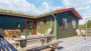 Une cabane en bois dotée d’une terrasse, de meubles de jardin et d’une table de pique-nique.