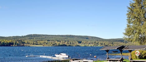 A lakeside park with picnic tables, a boat dock, and a lifebuoy sign.