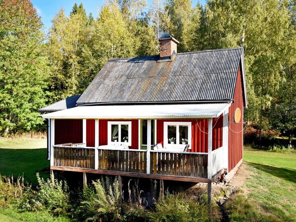 Une maison en bois rouge avec un balcon, entourée de verdure.