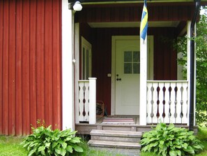 Ein Holzhaus mit weißer Tür und einer Veranda mit Geländer.