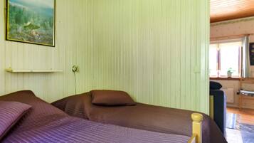 A room with two beds, a painting on the wall, and a window with a view.