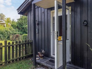 A wooden building with a door open, a small porch, and a sign on the door.