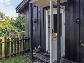 Een houten gebouw met een open deur naar een veranda.