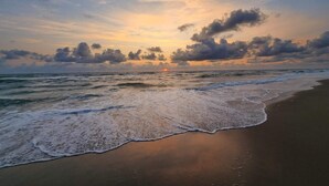 A beach with waves and a sunset.