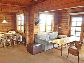 A log cabin interior with a dining area, sofa, and ottoman.