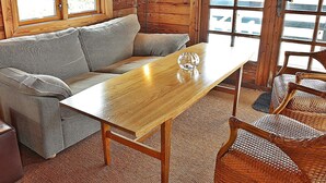 A wooden interior with a sofa, a table, and wicker chairs.