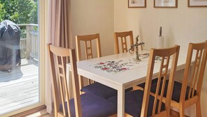 Una mesa de comedor con cuatro sillas, mantel floral y una ventana con cortinas.