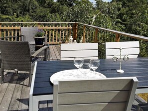 A deck with outdoor furniture, including a table with three wine glasses and a chair.