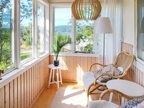 A cozy room with a view of a lake, a wicker chair, a small table, and a hanging light fixture. - 4 Person Holiday Home in Uddevalla (Uddevalla)