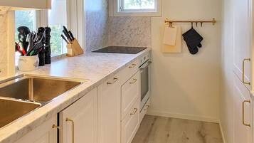 A compact kitchen with white cabinetry, a stainless steel sink, and a window above the countertop.