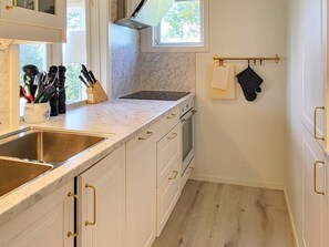 A compact kitchen with white cabinetry, a stainless steel sink, and a window above the countertop. - 4 Person Holiday Home in Uddevalla (Uddevalla)