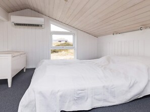 Ein Schlafzimmer mit einem Bett, einem Nachttisch, einer Klimaanlage und einem Fenster mit Blick ins Freie.