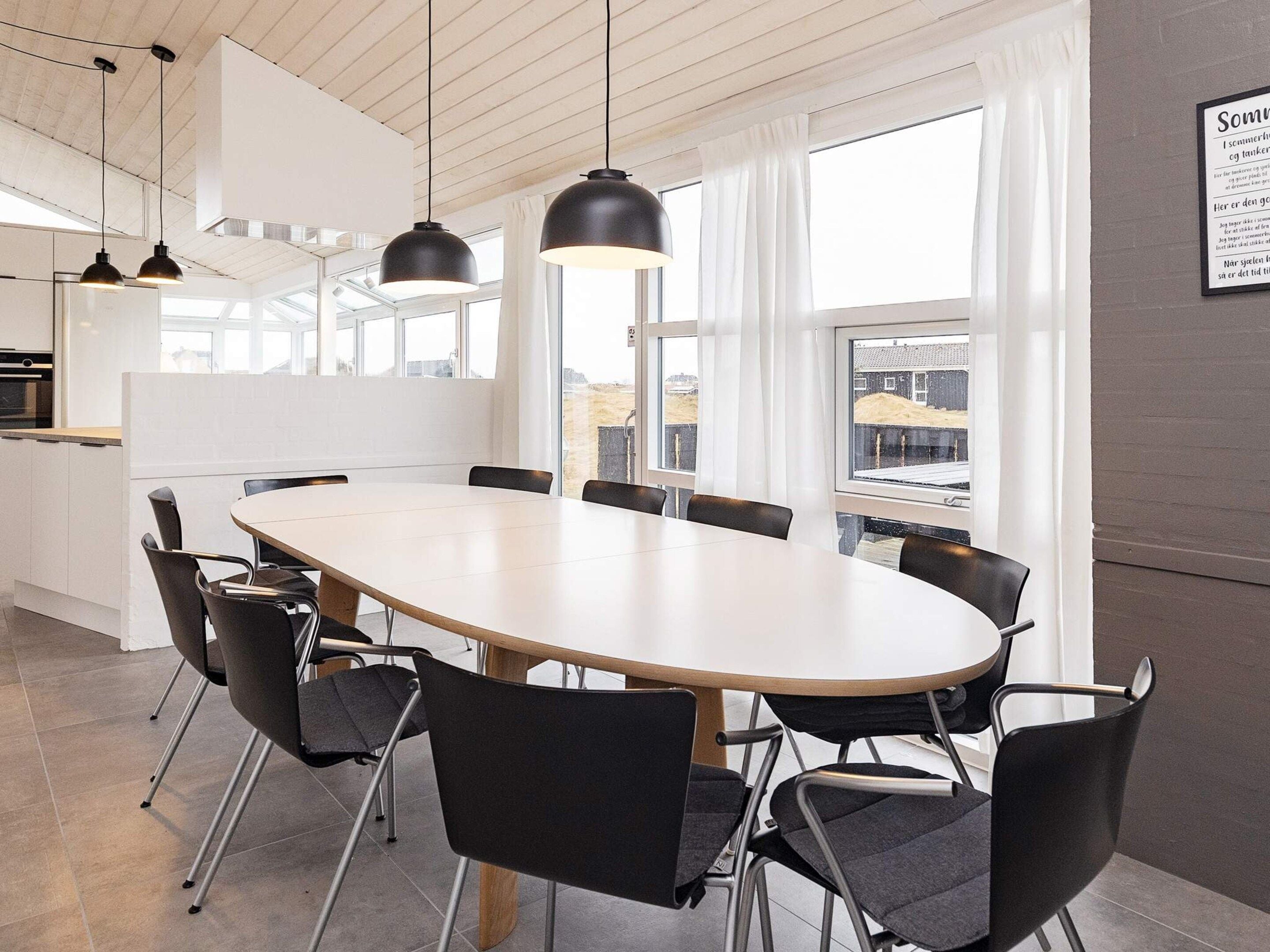 Een moderne vergaderzaal met een grote ovale tafel, zwarte stoelen, hangende lampen en ramen met uitzicht op de stad.