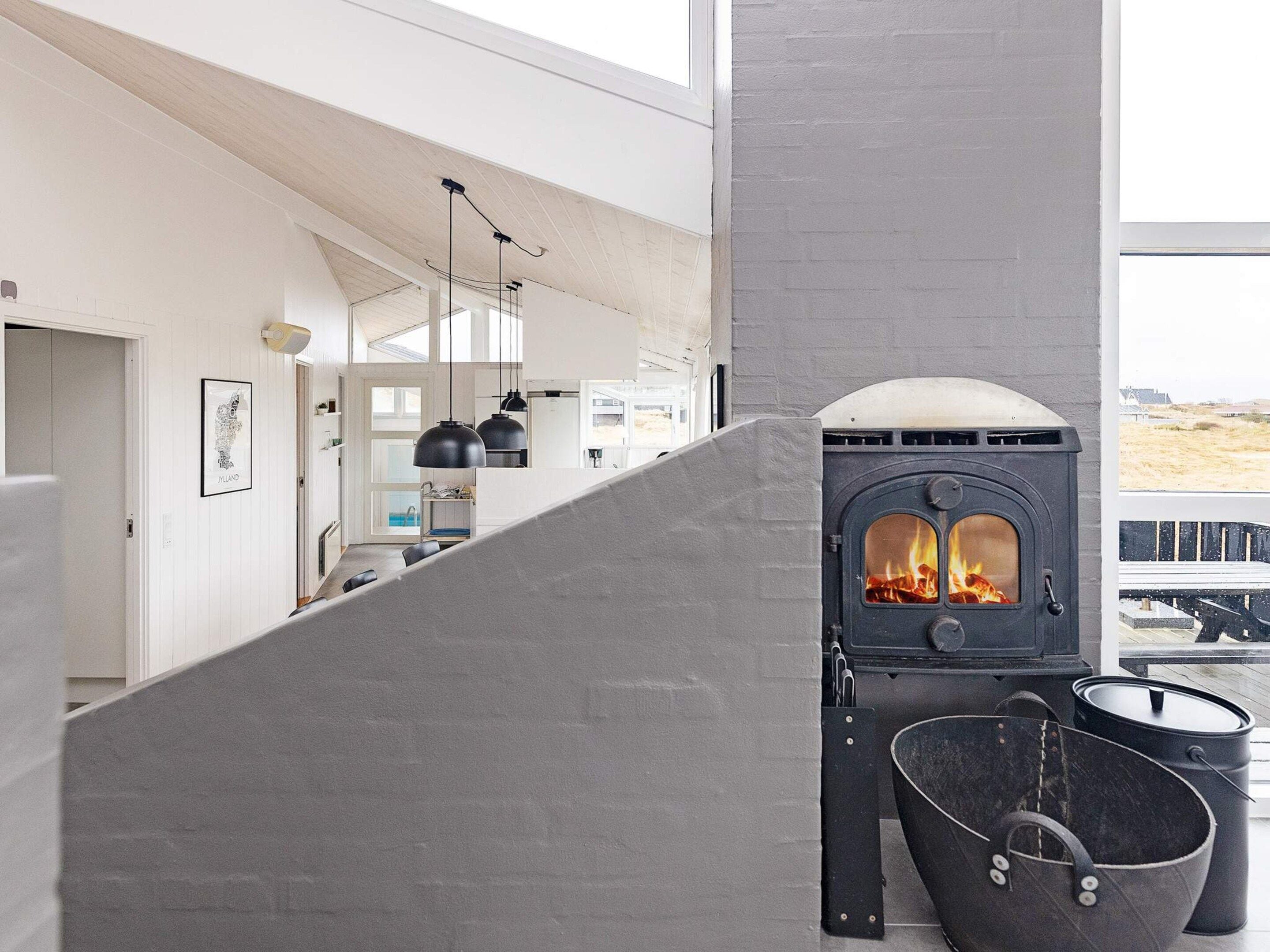 A modern interior with a fireplace, pendant lights, and a view of the outdoors.