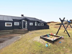 Ein schwarzes Gebäude mit Veranda und einem Spielbereich mit Spielzeug.
