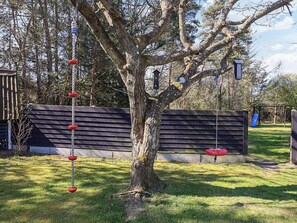A tree with a swing set and a slide.