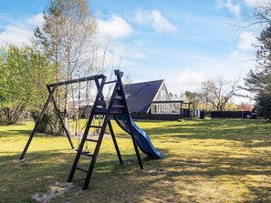 A playground with a swing set and slide in a grassy yard.
