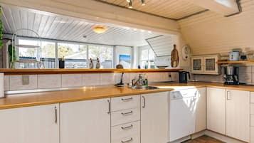 A kitchen with wooden cabinets, a sink, and a coffee maker.