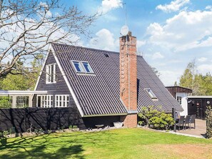 Une maison avec un toit en pente, une cheminée en briques et une antenne parabolique.