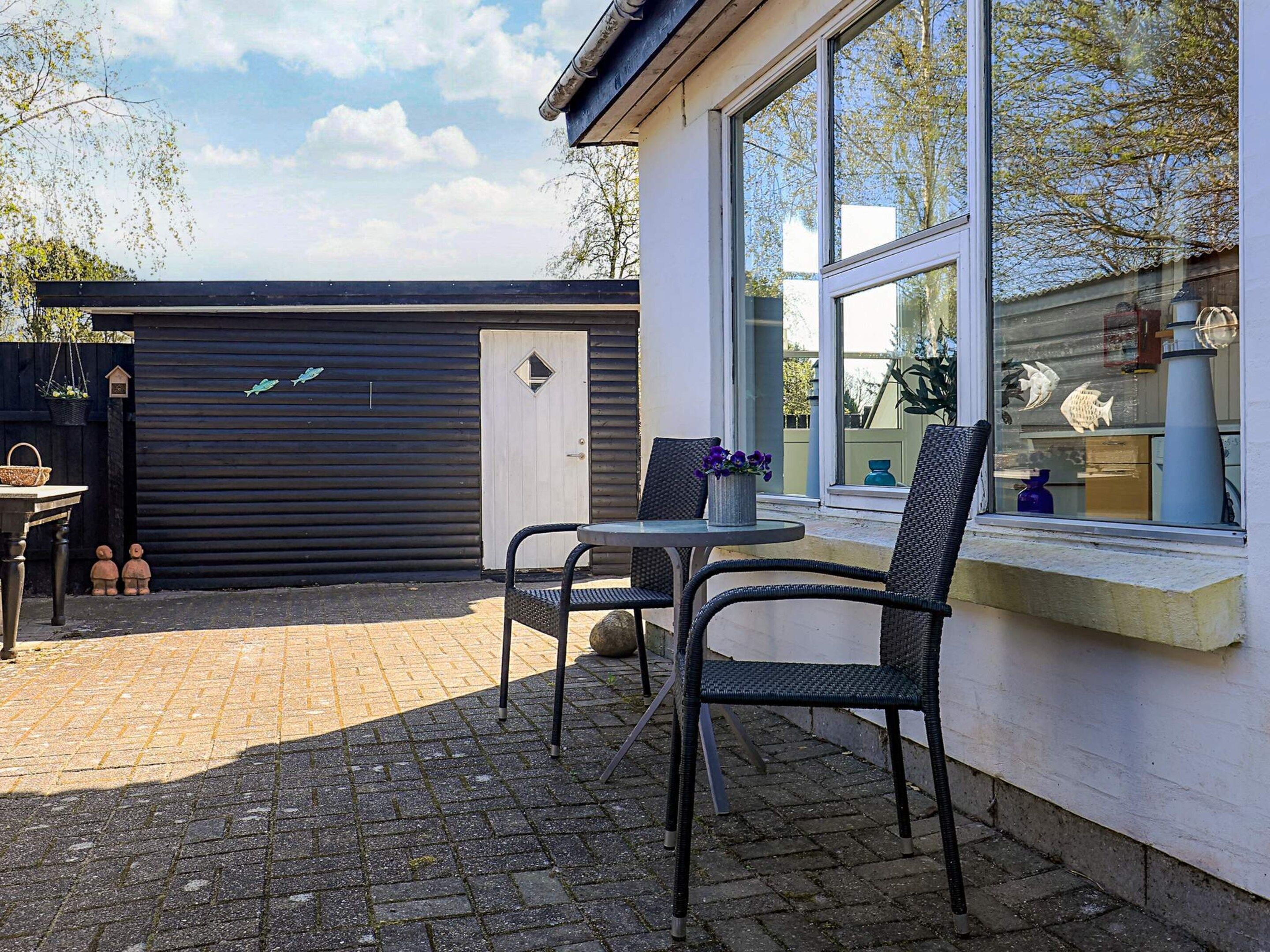 Une terrasse avec une table et des chaises, une fenêtre ornée de poissons décoratifs et une porte de garage.