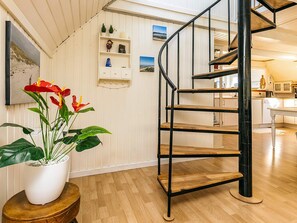 A spiral staircase with wooden steps and black metal railings in a room with wooden flooring and white walls.