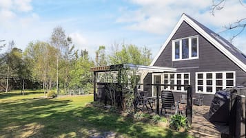A residential house with a sloped roof, large windows, and a covered patio area.