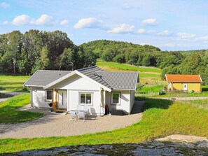 A two-story white building with a gravel driveway and a small patio area. - Holiday Home in Ljungskile (Ljungskile)